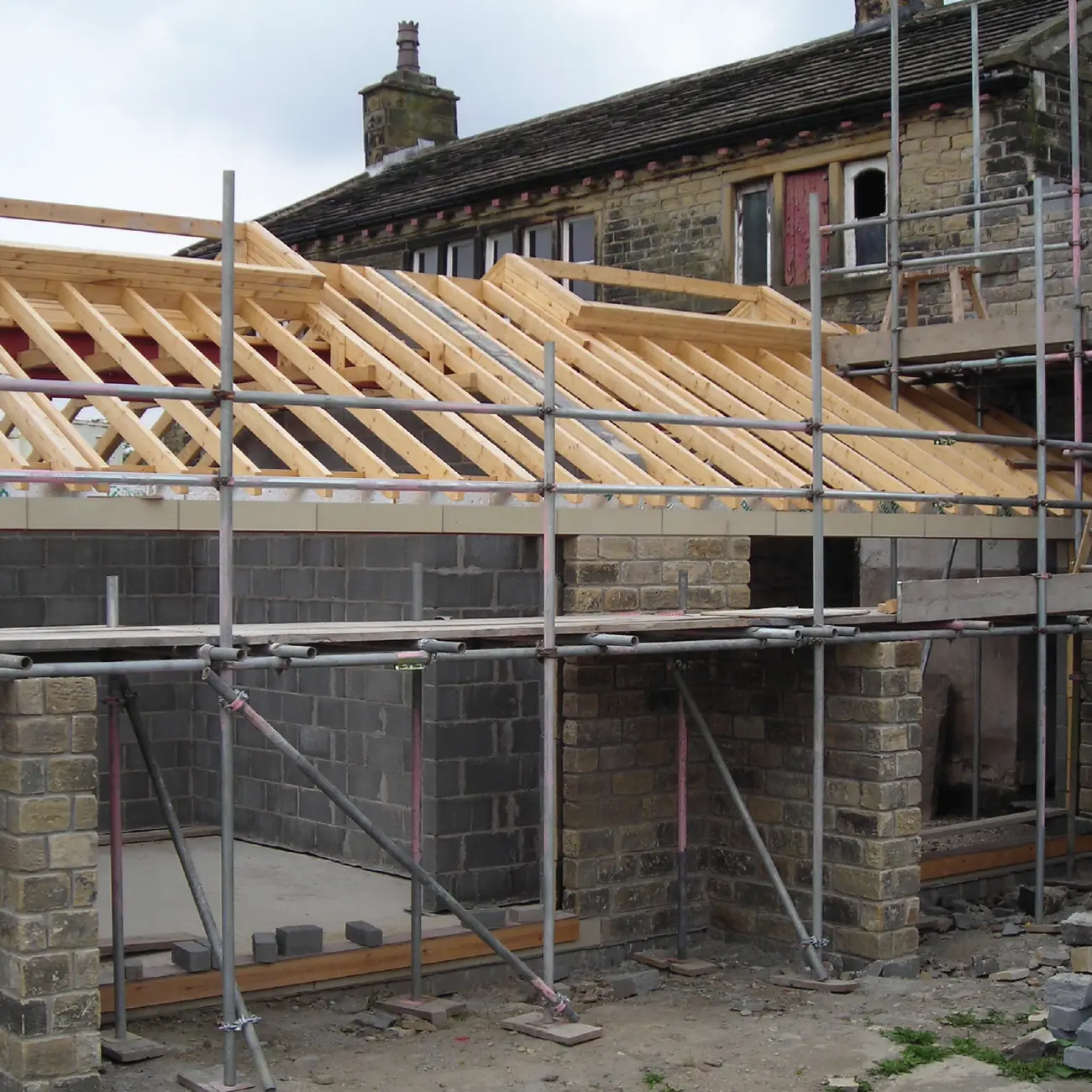 Barn and outbuilding under construction with new roof structure and scaffolding