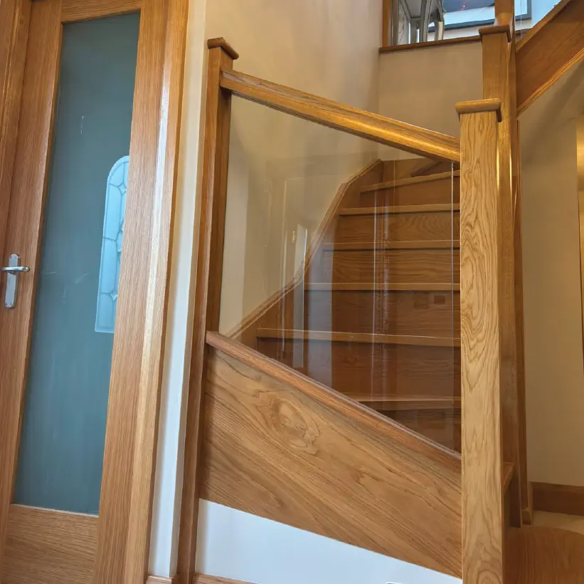 Oak glazed door beside an oak and glass staircase balustrade