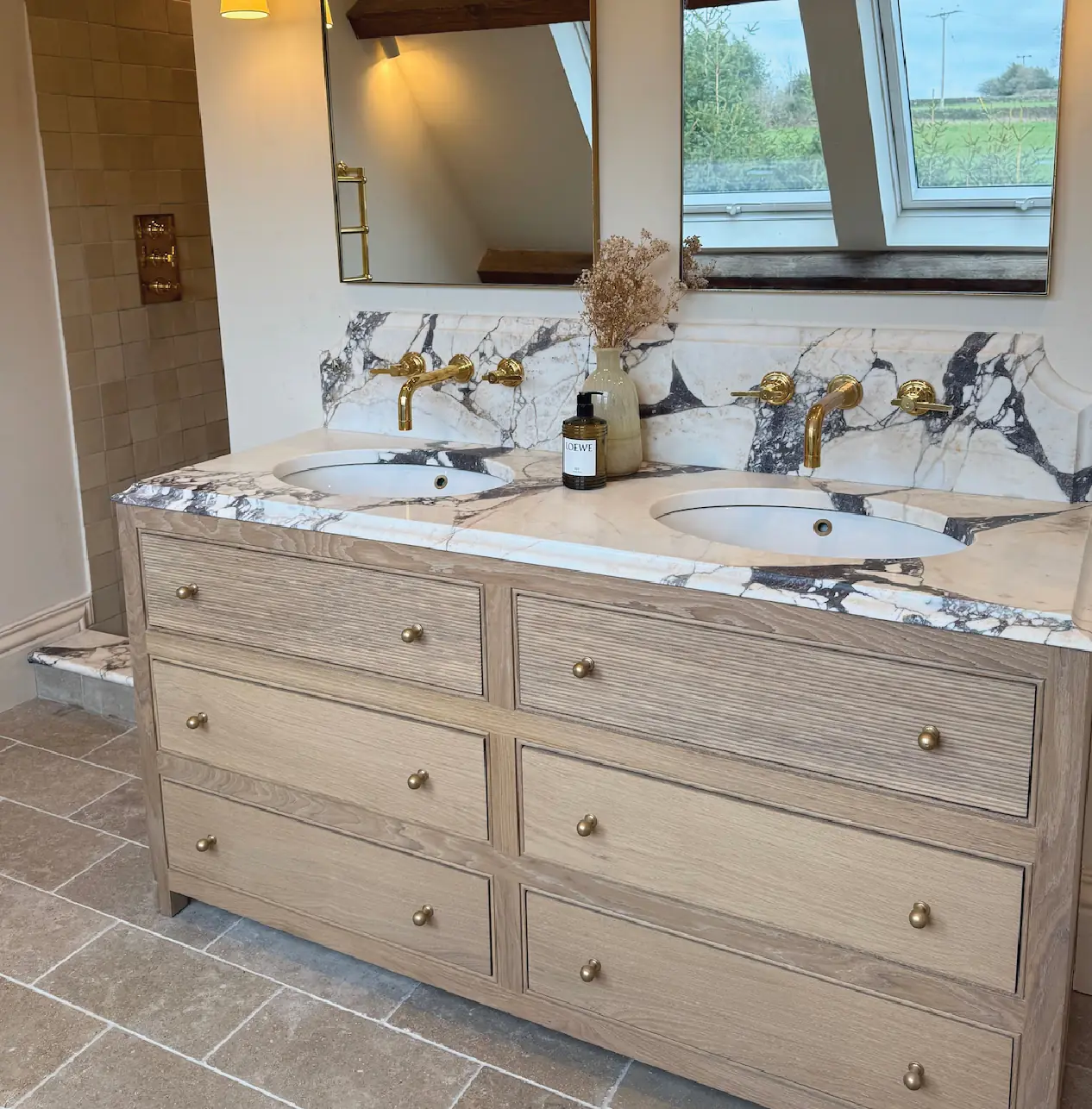 Bespoke twin vanity unit with a marble top under a beamed ceiling