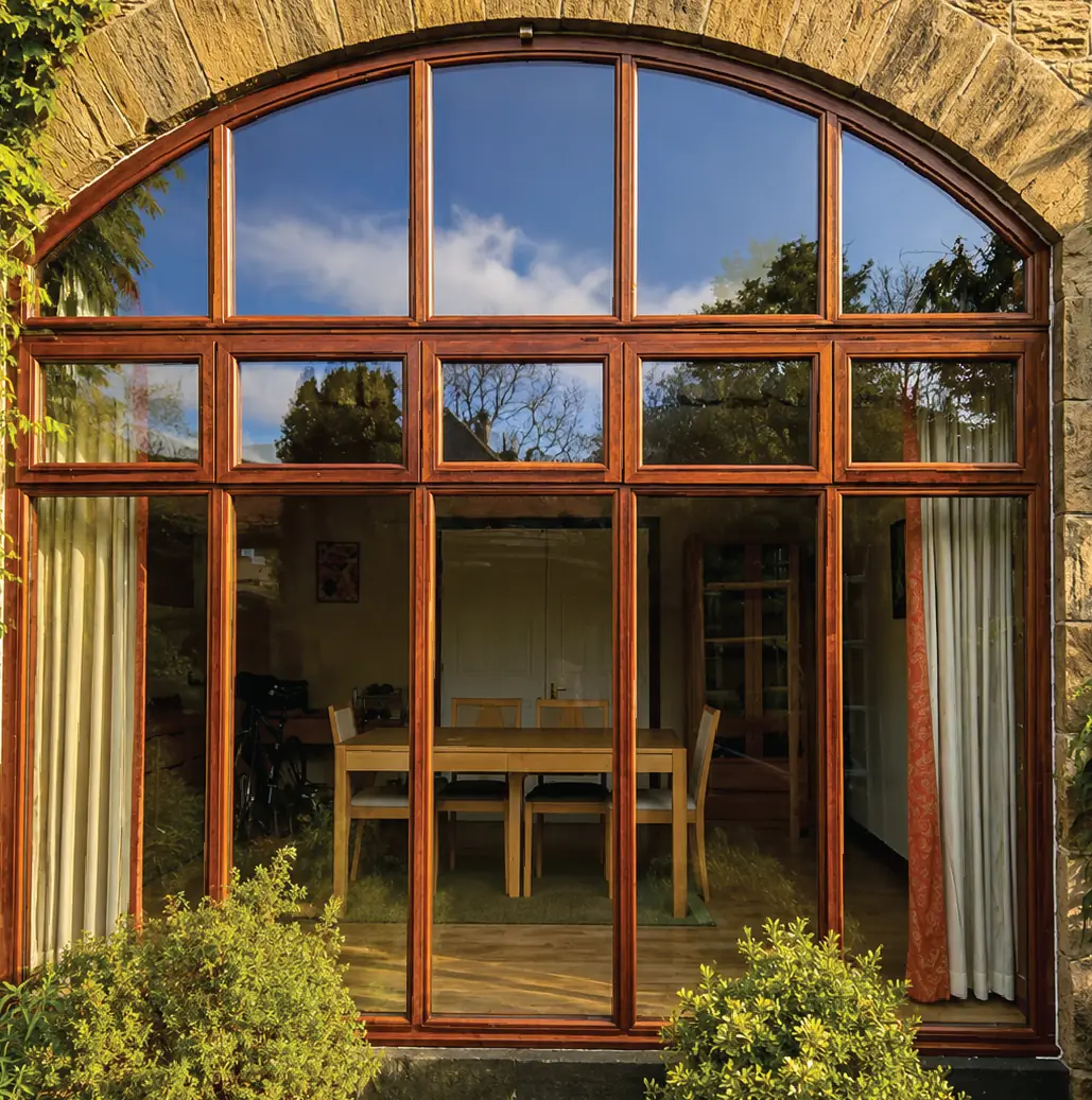 Arched hardwood window and doors opening from a dining room onto the garden