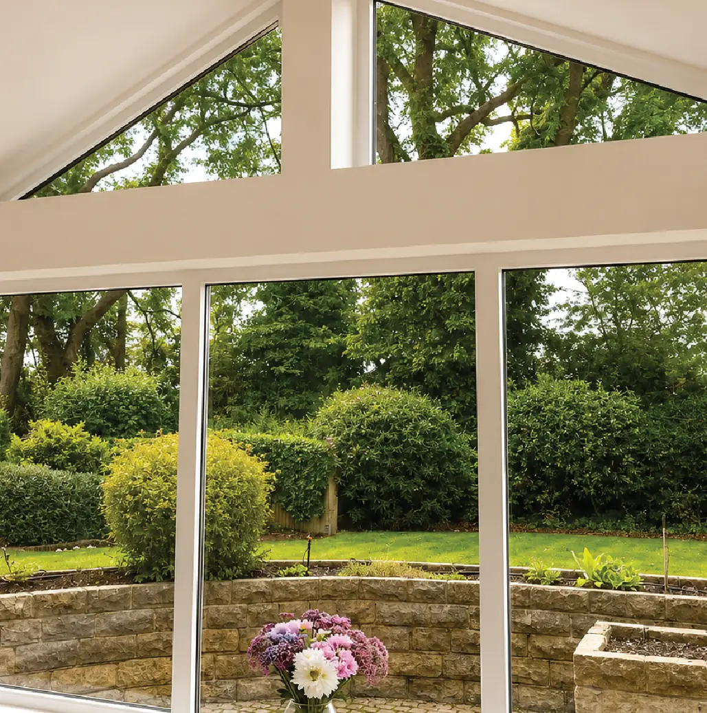 Painted gable glazing to a garden room, framing the planted borders beyond